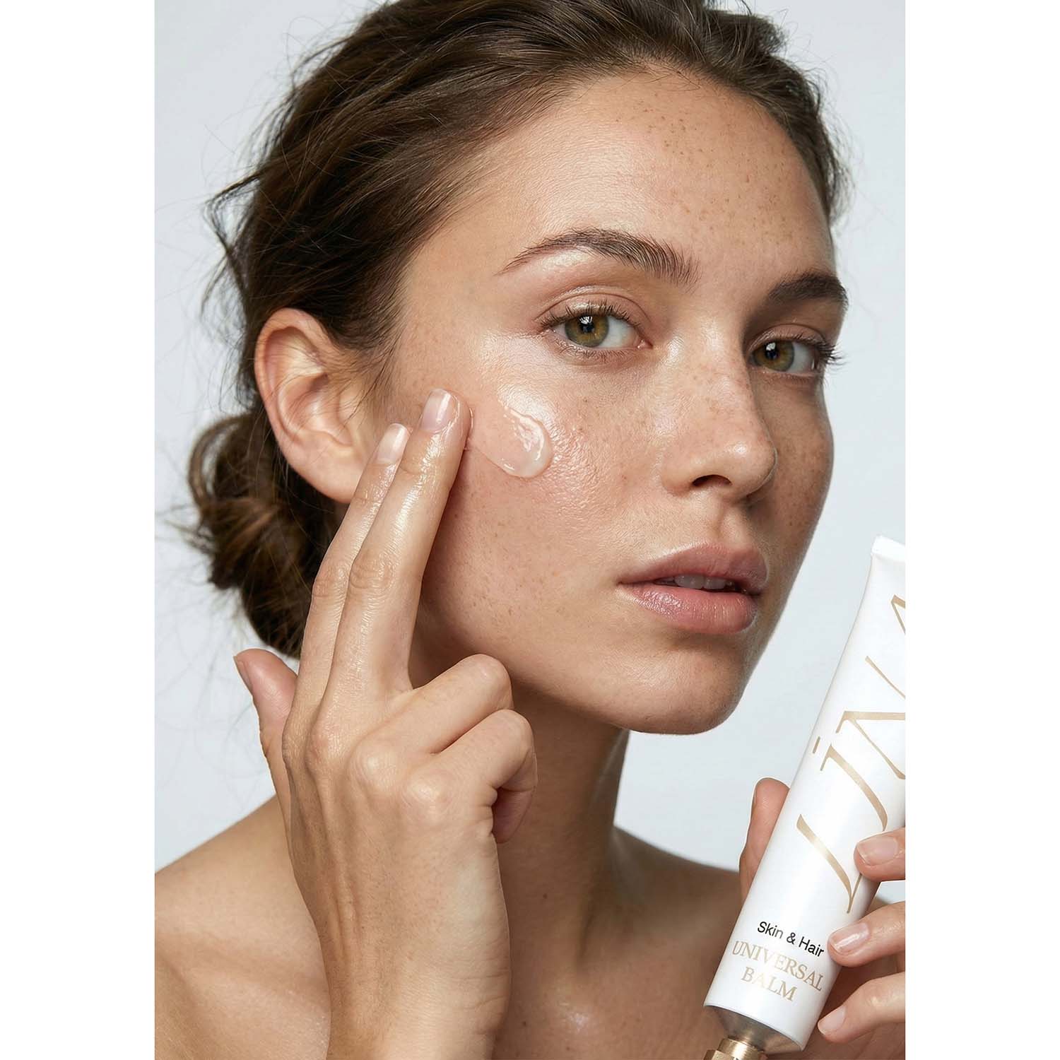 Woman applies LINA Universal Balm to his cheek. 